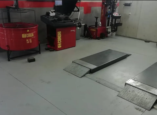 Officina meccanica con attrezzature per il cambio gomme, equilibratrice per ruote e binari per il sollevamento dei veicoli.
