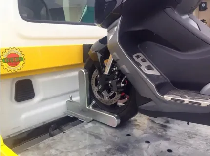 La ruota anteriore di una motocicletta è fissata in un cuneo metallico montato sul pianale di un carro attrezzi.