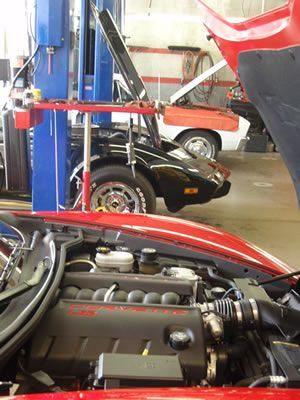 A red car with its hood open in a garage