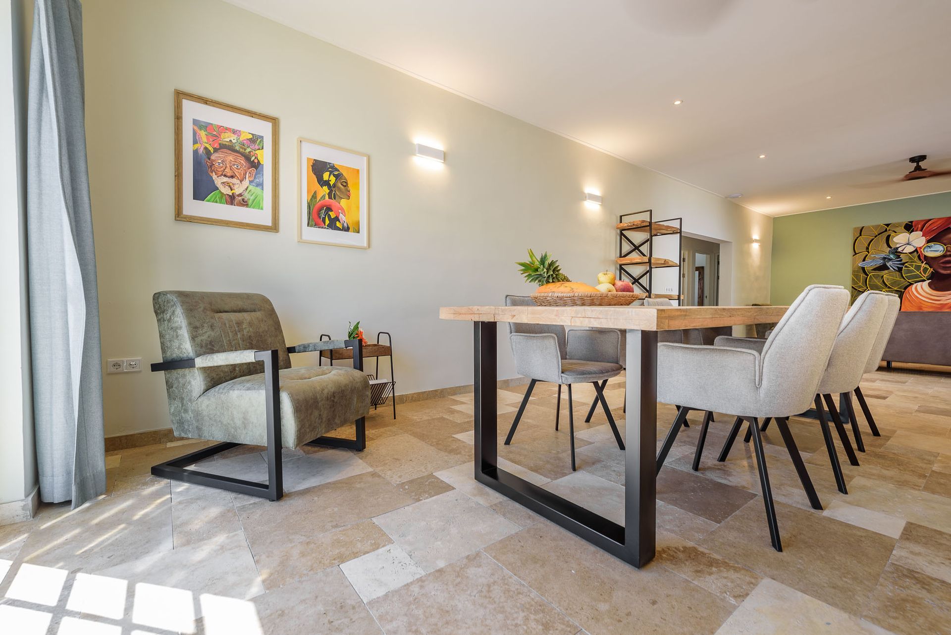 Dining room with wood table, gray chairs, artwork, and accent chair.