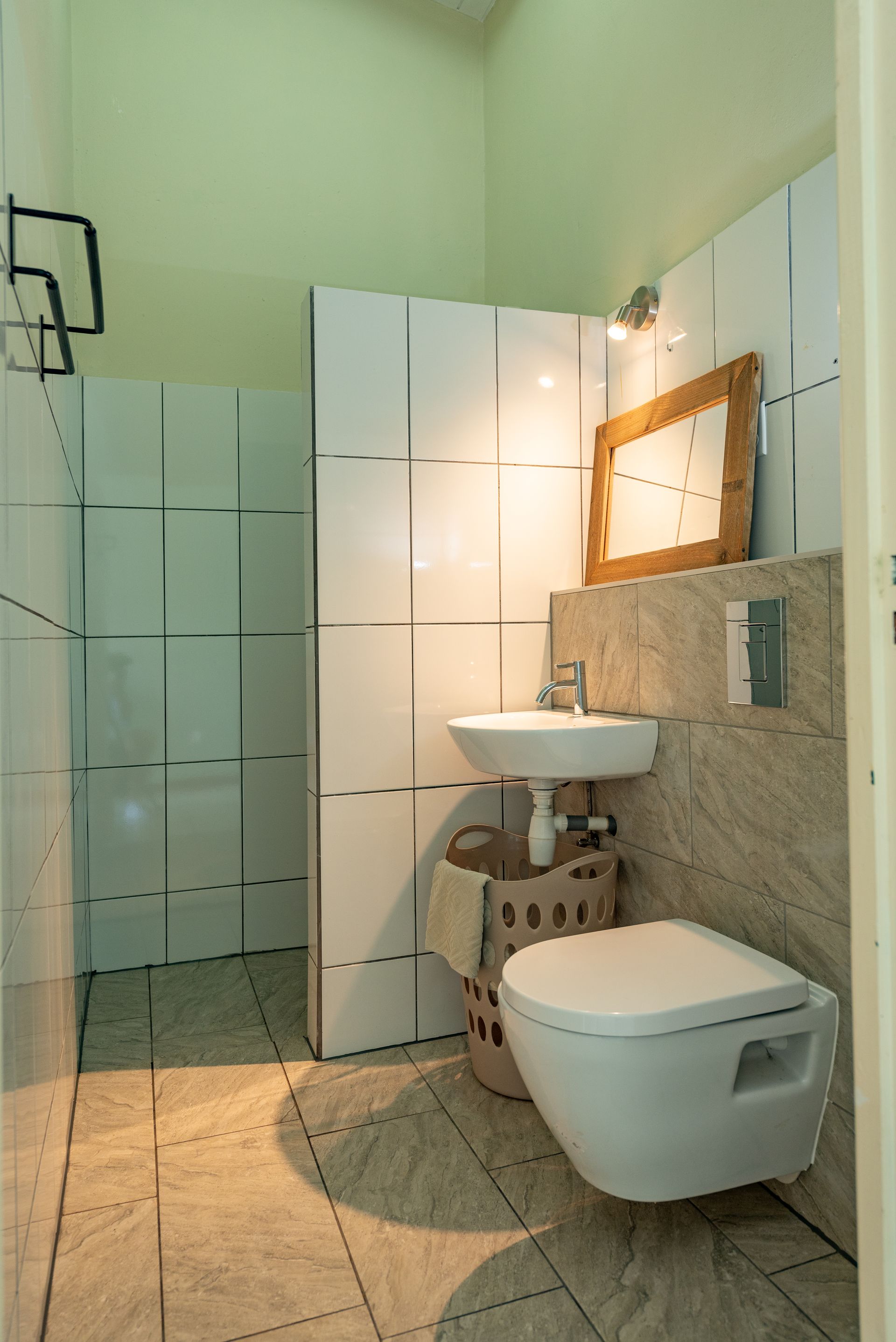 Small bathroom with white and beige tile, wall-mounted toilet, sink, and decorative walls.