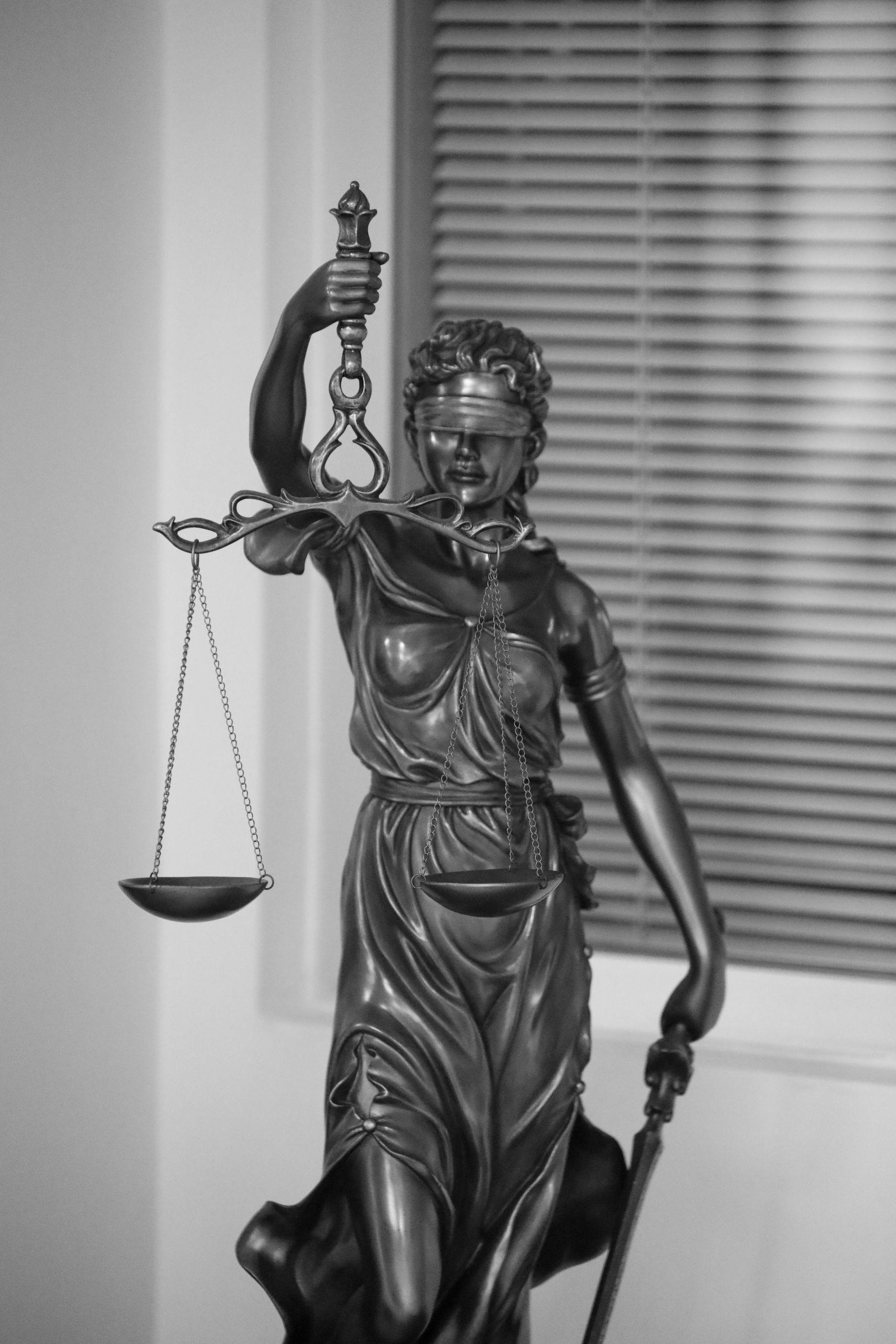 Statua della Giustizia con bilancia e spada, bendata.