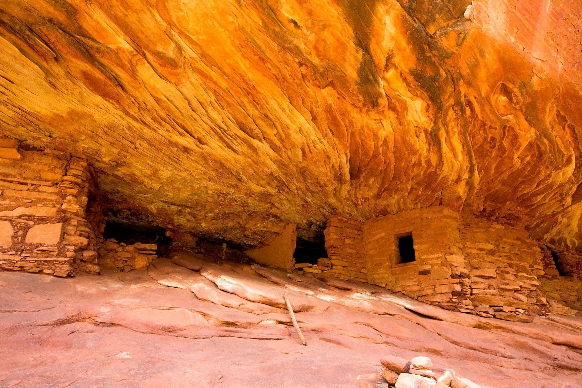 Ancient dwelling site with red rocks in a canyon crevice, the rock above it looks like fire burning