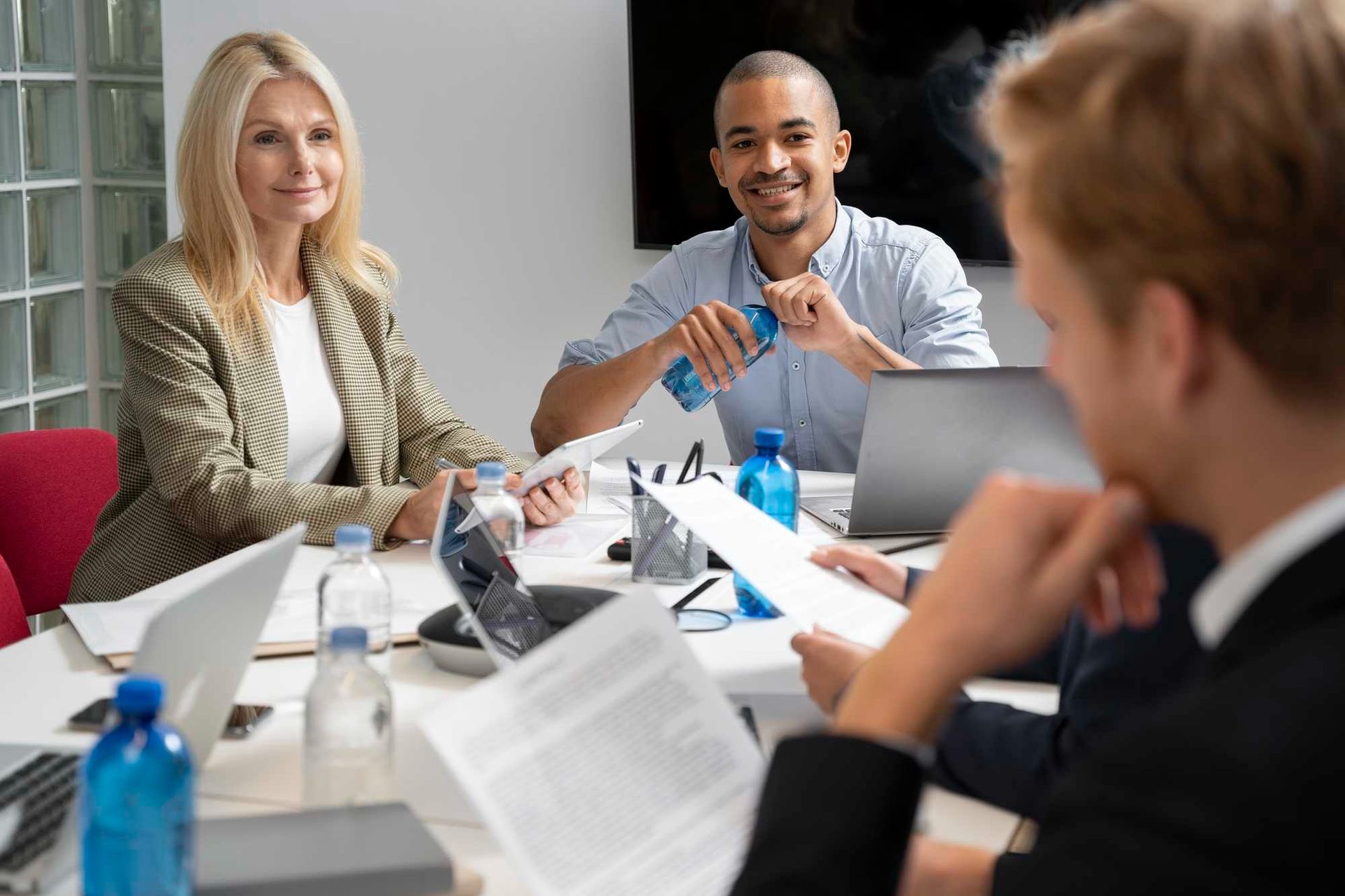 Team meeting around a conference table with laptops and documents in a bright office