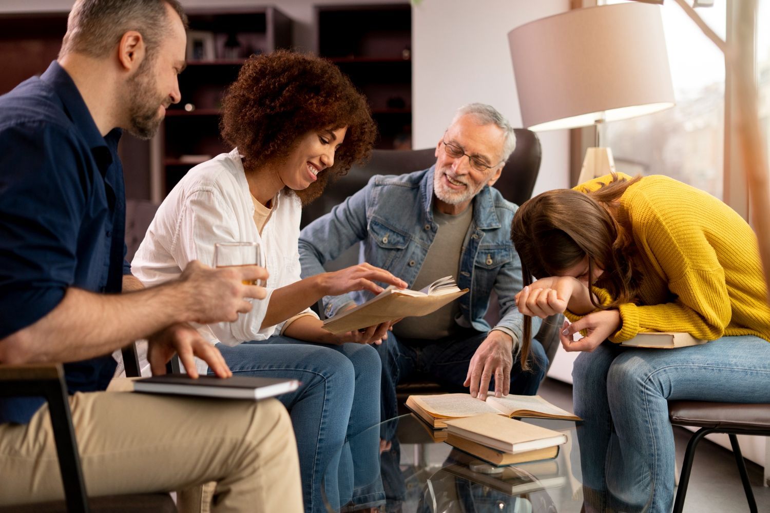 Group seated in a living room, discussing papers around a coffee table while one person writes notes
