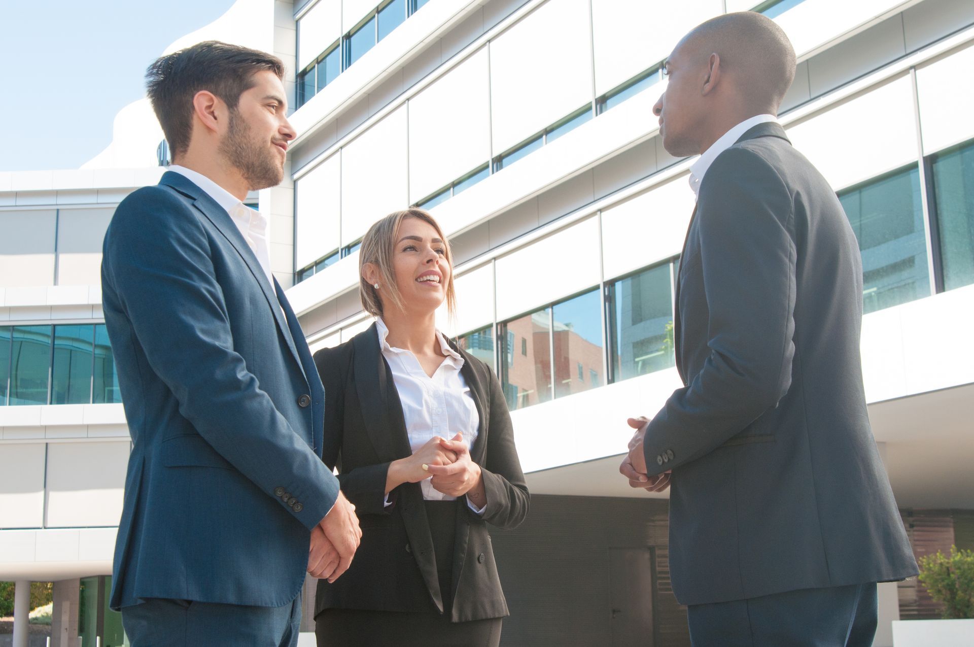 Three professionals talking outside a modern office building