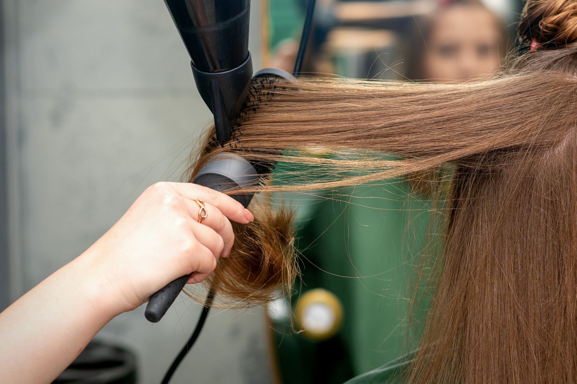 Stylist blow-drying and brushing long hair in a salon. Stylist blow-drying and brushing long hair in a salon.