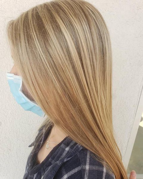 A woman with long blonde hair is wearing a mask.