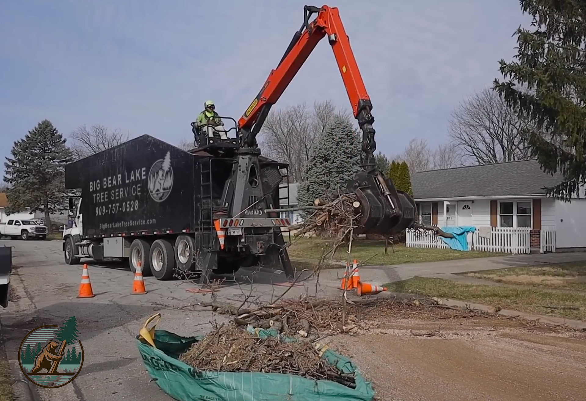 A Big Bear Lake Tree Service crane operator using a crane claw to remove tree debris from a homeowner's yard