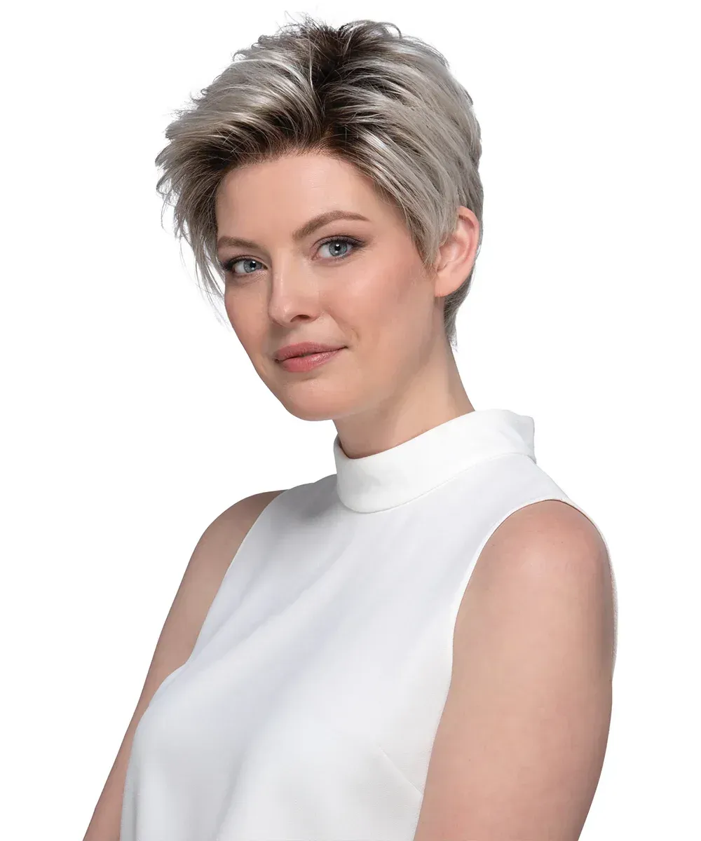 Woman with short, layered blonde wig smiles; wearing a white sleeveless top.