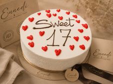 Torta con un orsacchiotto sopra, glassa rosa, decorazioni a forma di cuore.