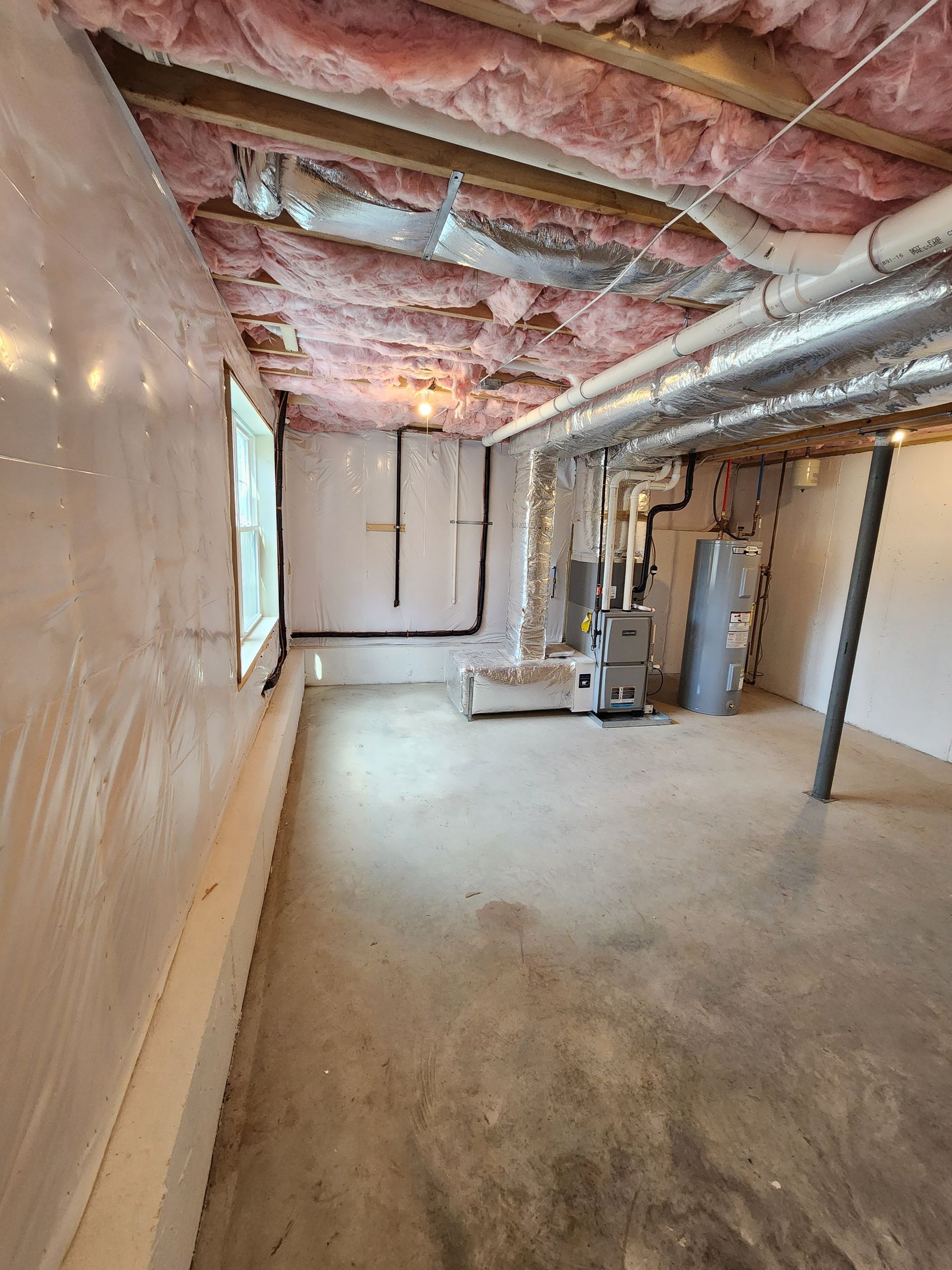 An empty basement with a lot of pipes coming out of the ceiling.