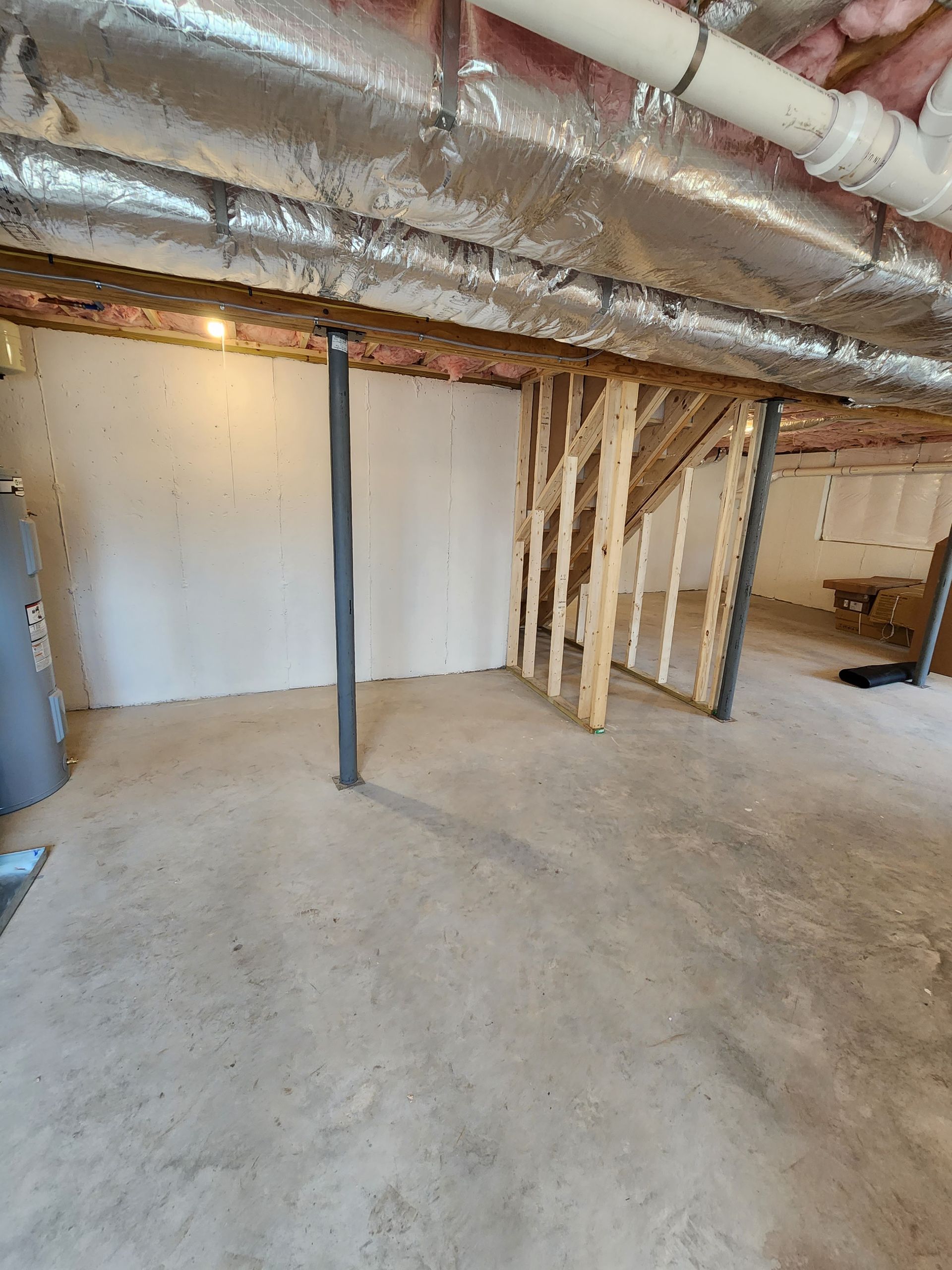 An empty basement with a lot of pipes coming out of the ceiling.