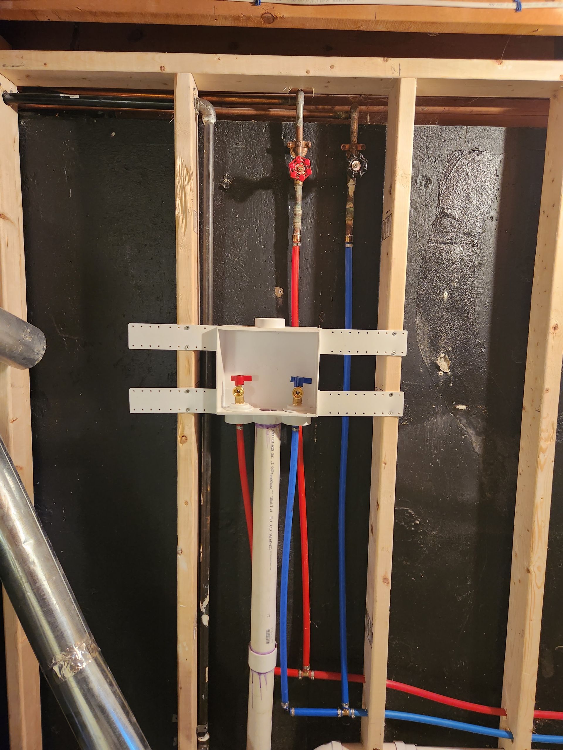A bathroom under construction with a drain box and pipes.