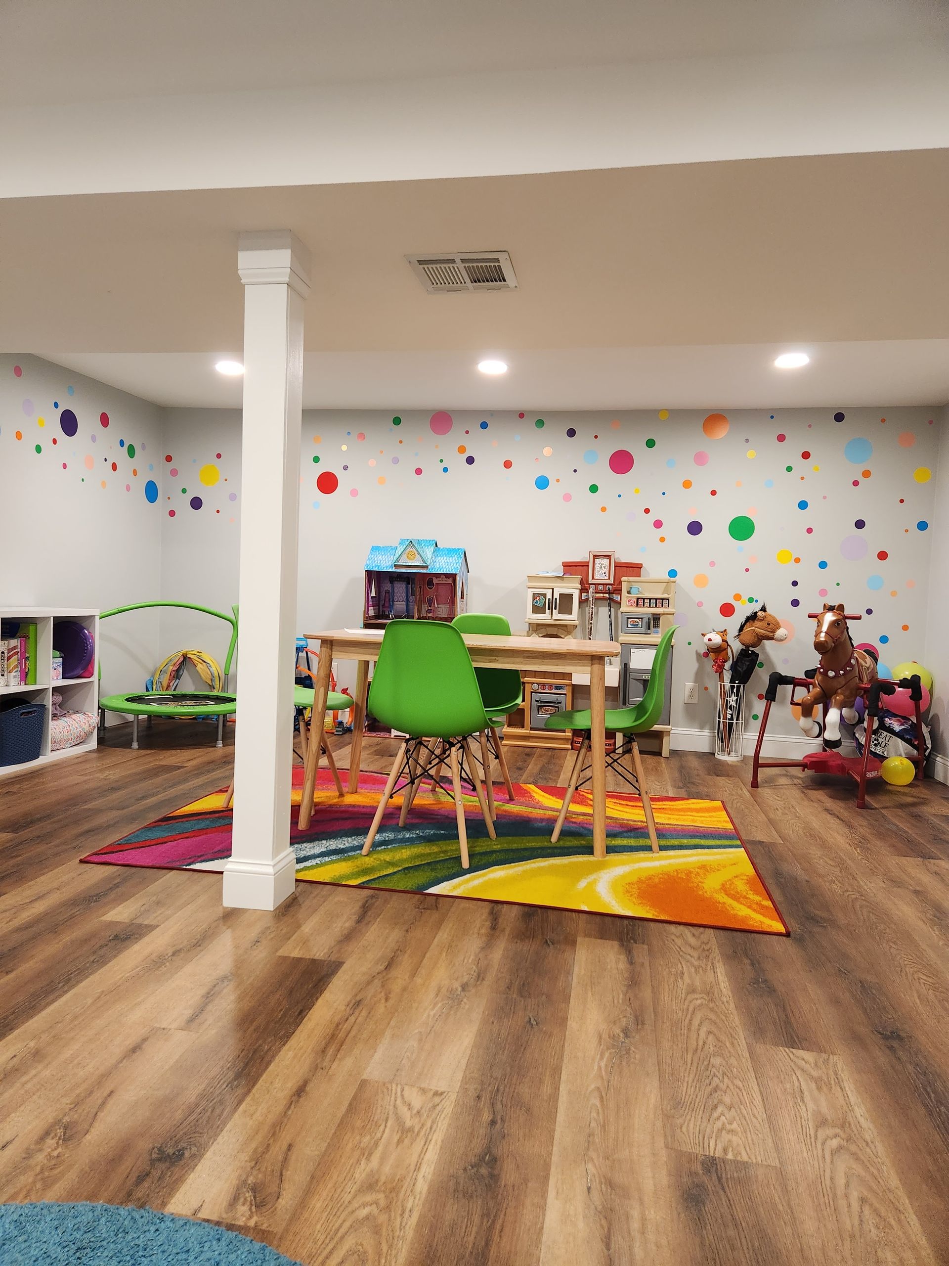 A play room with a table , chairs , and a rug.