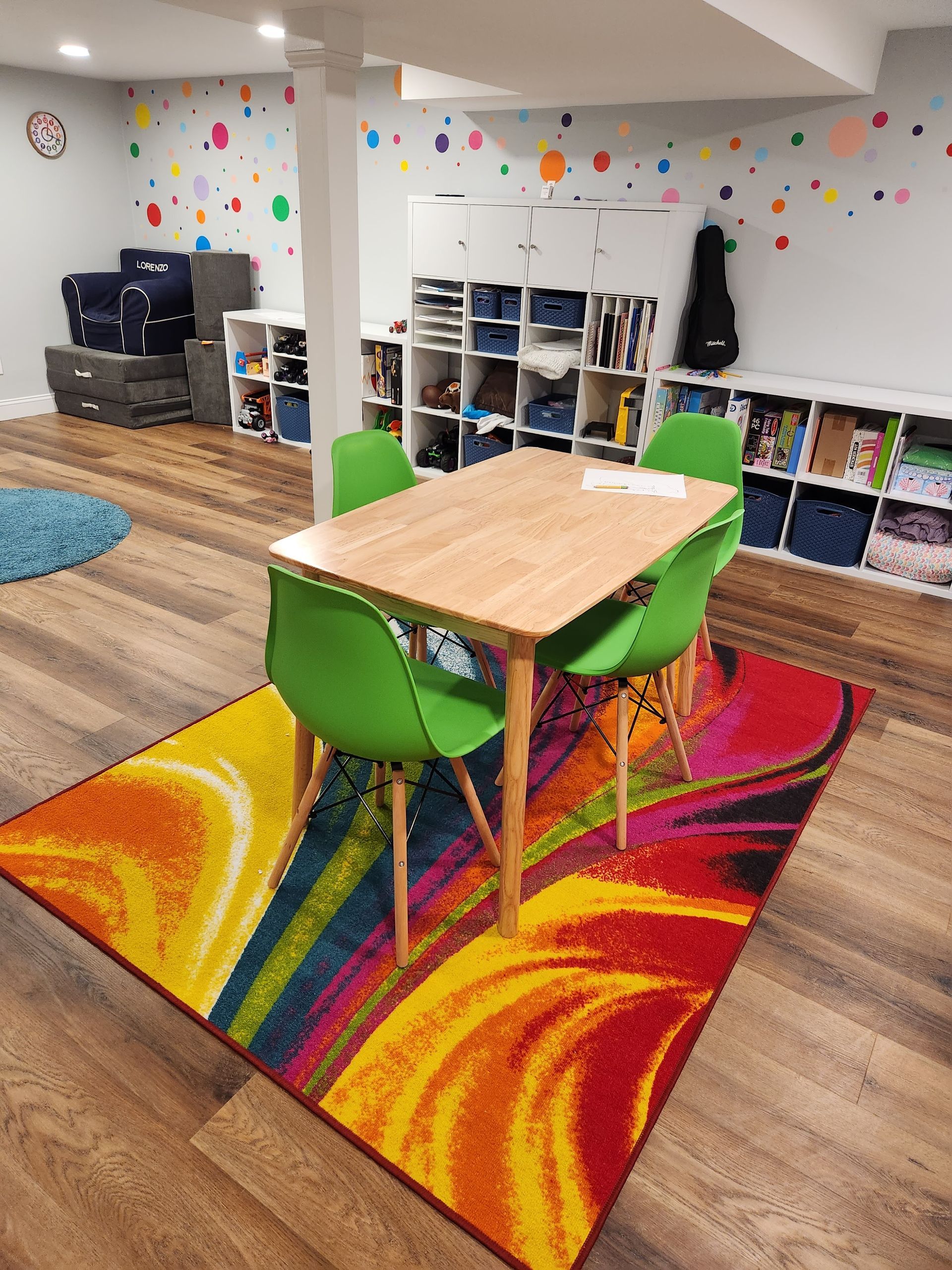 A dining room with a table and chairs and a colorful rug.