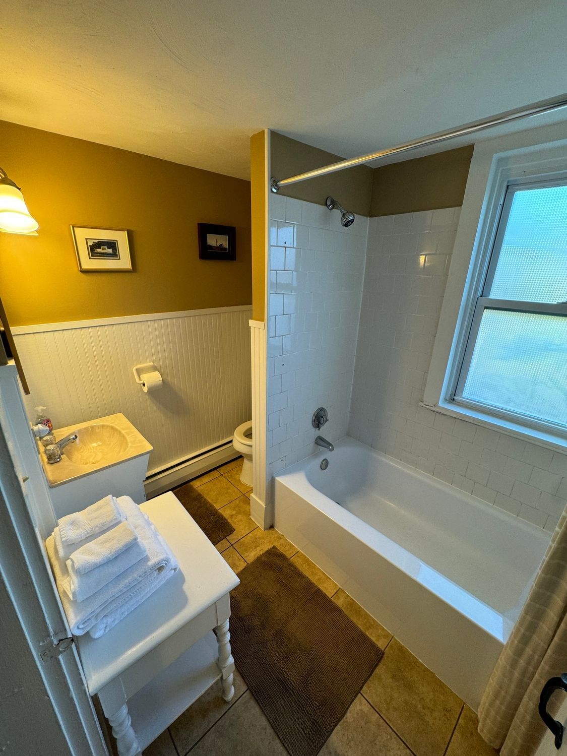 A bathroom with a tub , sink , toilet and window.