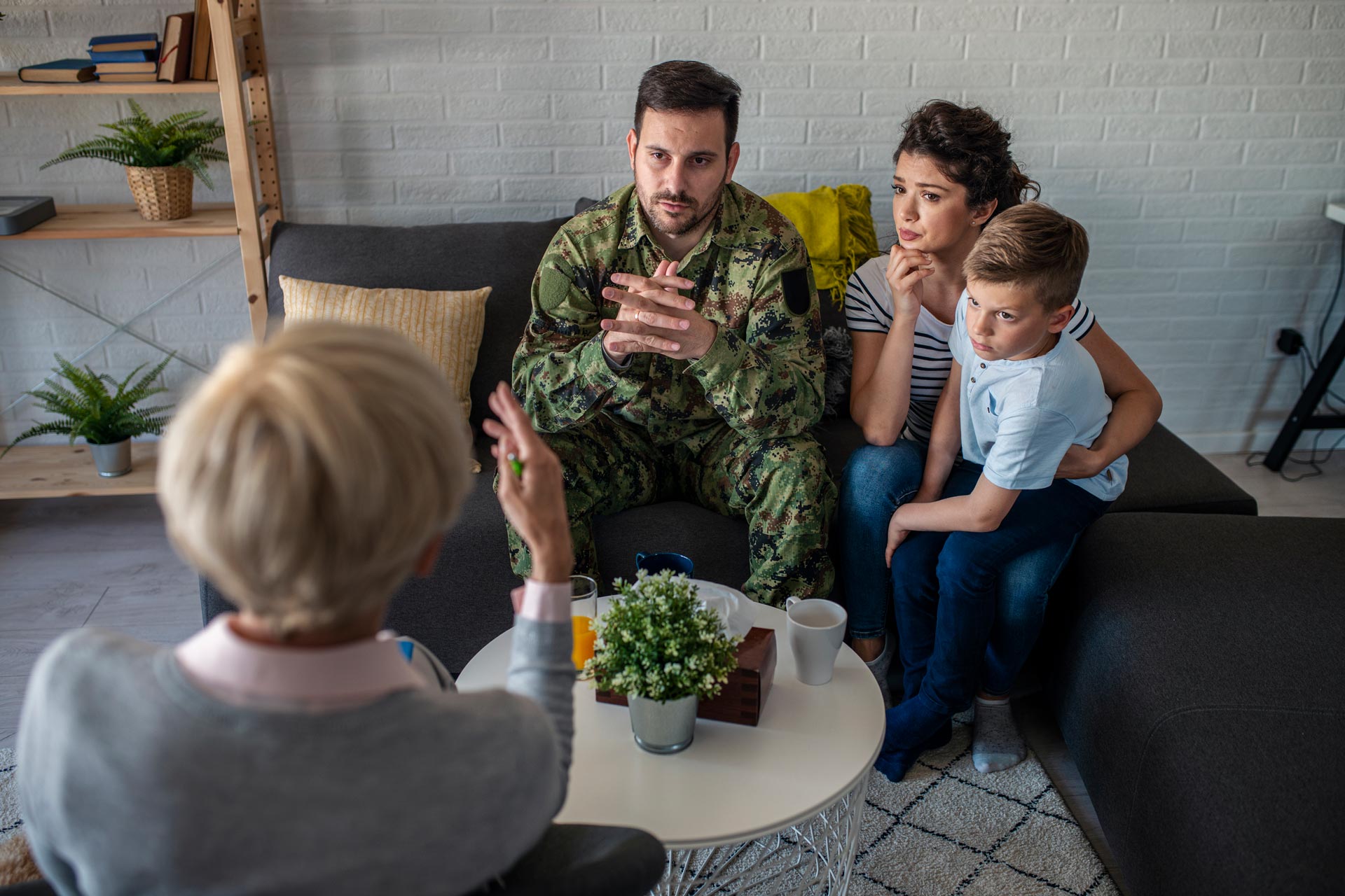 Family talking with a counselor in a living room during a therapy session