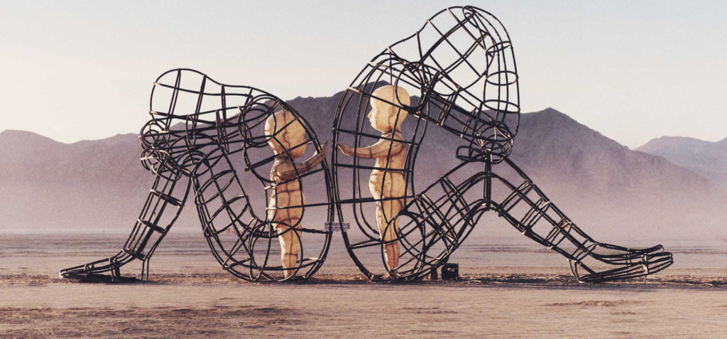 Wireframe sculpture of a crouching elephant in a desert landscape at sunset