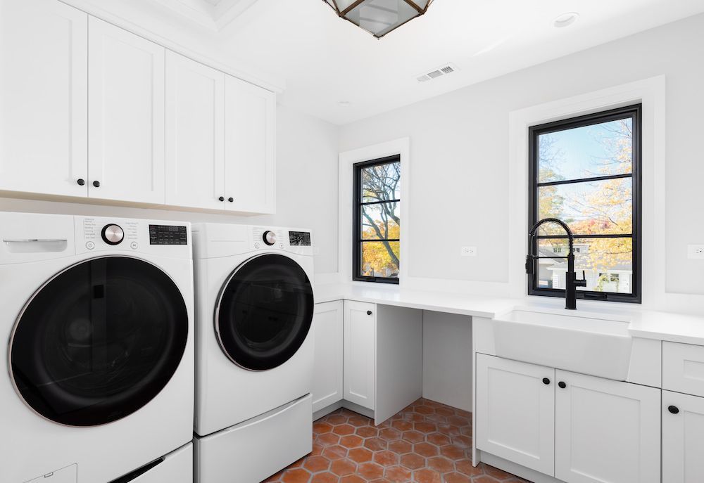 White Laundry Room With Washer, Dryer, Cabinets, Windows, and Sink — Kolora Projects in Robina, QLD