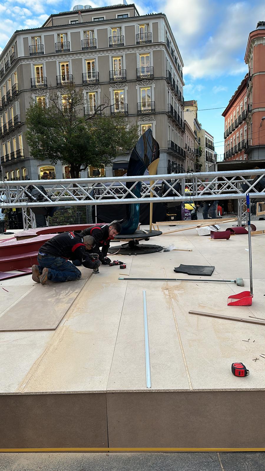 Un hombre está arrodillado sobre un piso de madera frente a un edificio.