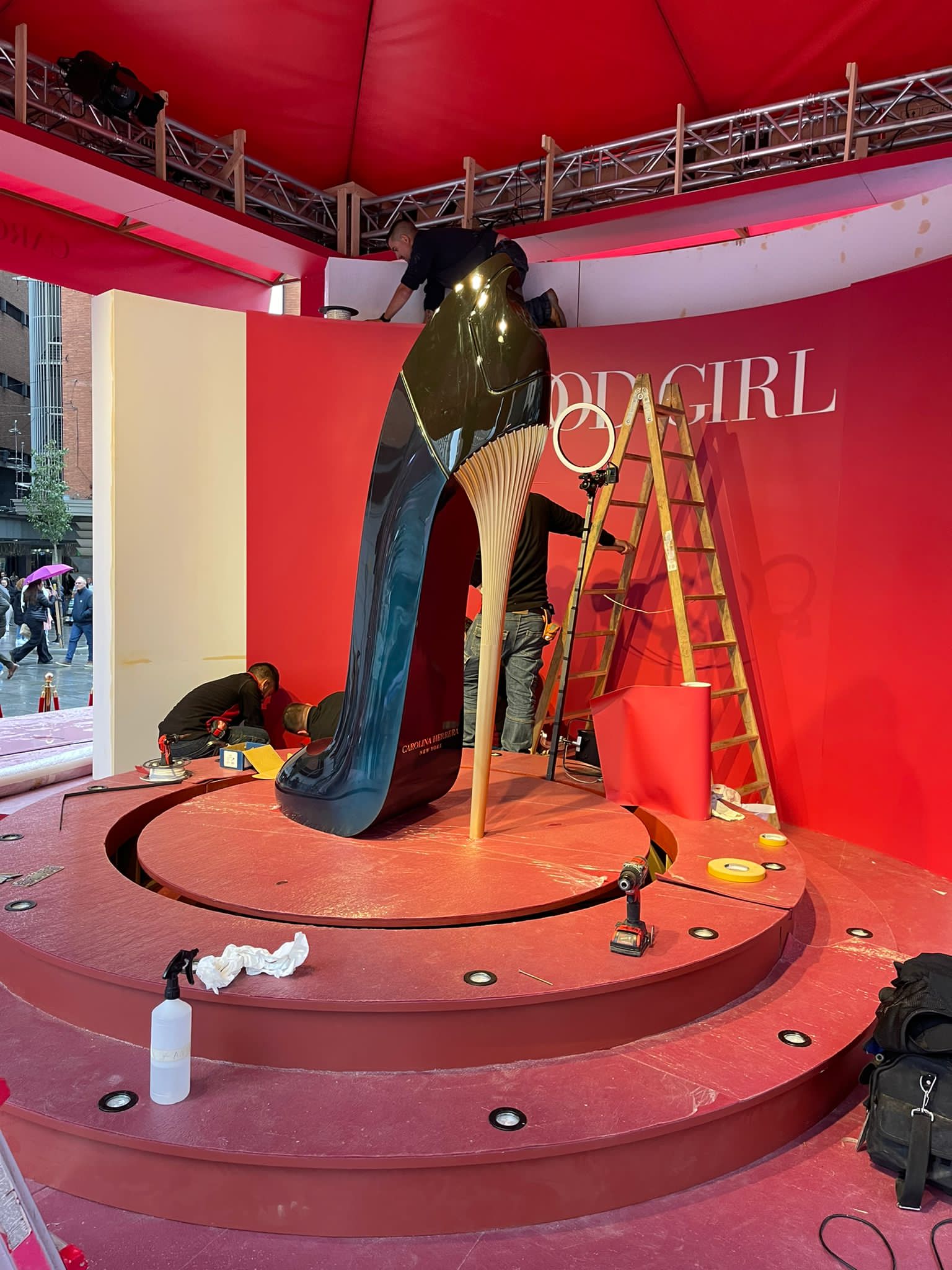 En un escenario se está construyendo una gran estatua de un zapato de mujer.