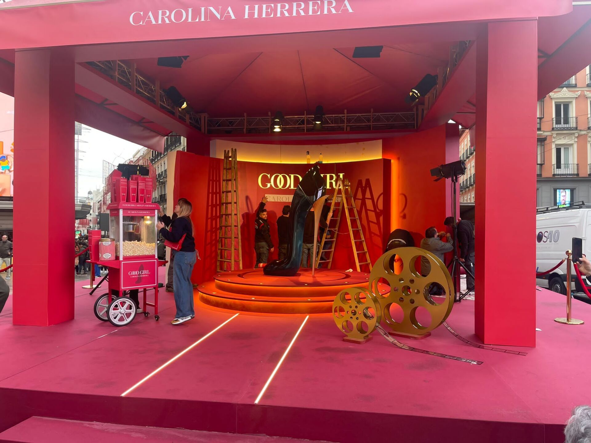 Un grupo de personas está trabajando en un escenario frente a una tienda de Carolina Herrera.