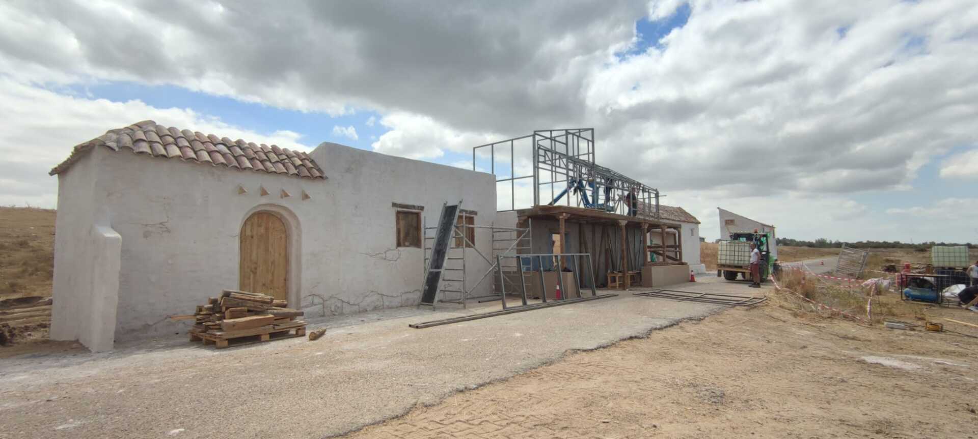 Se está construyendo un edificio blanco en medio de un campo de tierra.