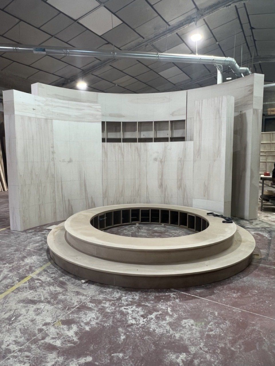 Se está construyendo una gran estructura circular de madera en un almacén.