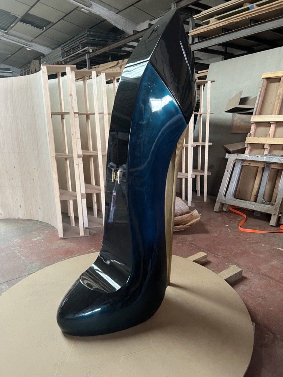Un zapato azul grande está encima de una caja de cartón en un almacén.