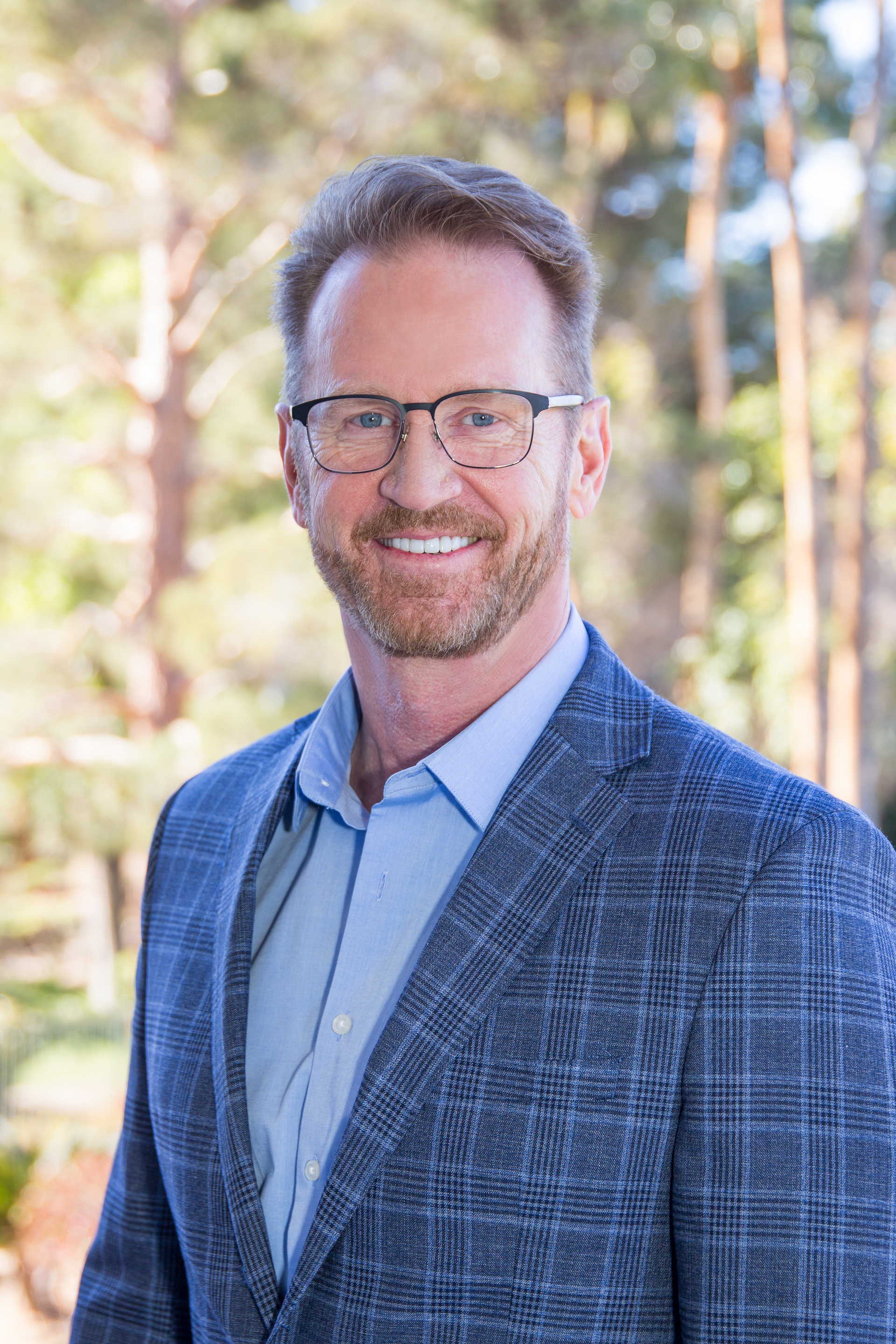 A man in a suit and glasses is smiling for the camera.