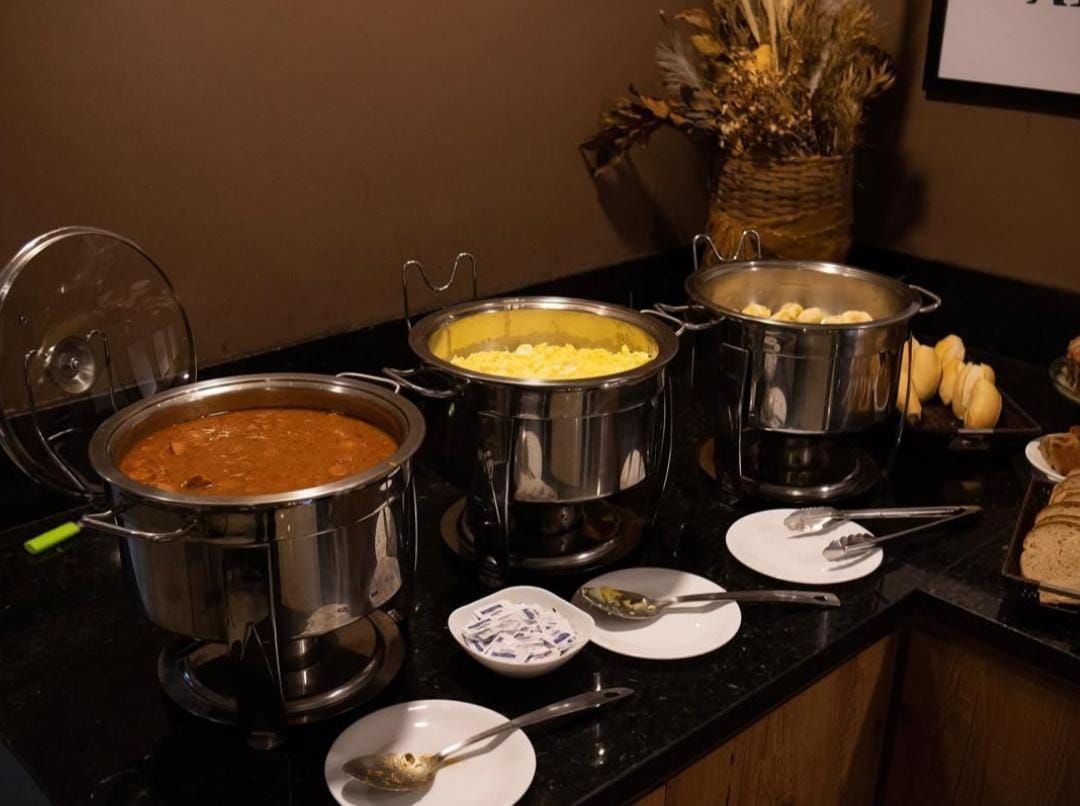 Buffet com três rechauds de aço inoxidável: chili, ovos mexidos e batatas.