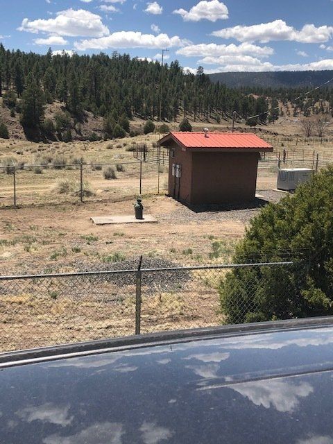 A small building with a red roof is in the middle of a field