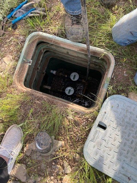A manhole cover is open and filled with water.