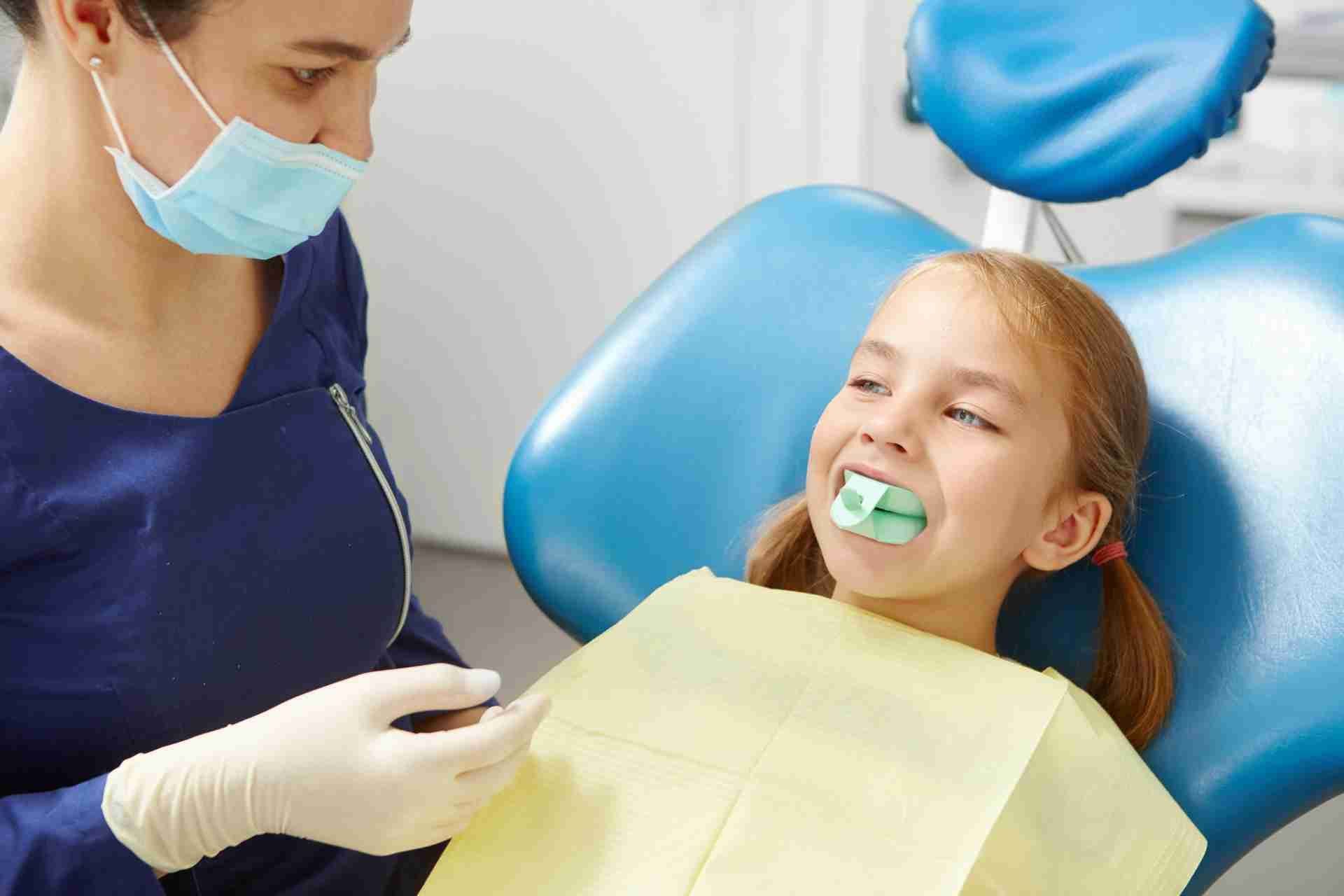 Dentist examining a smiling patient in a dental chair with a yellow bib