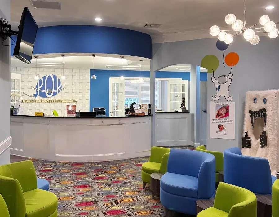 Bright pediatric clinic waiting room with colorful chairs and a curved reception desk