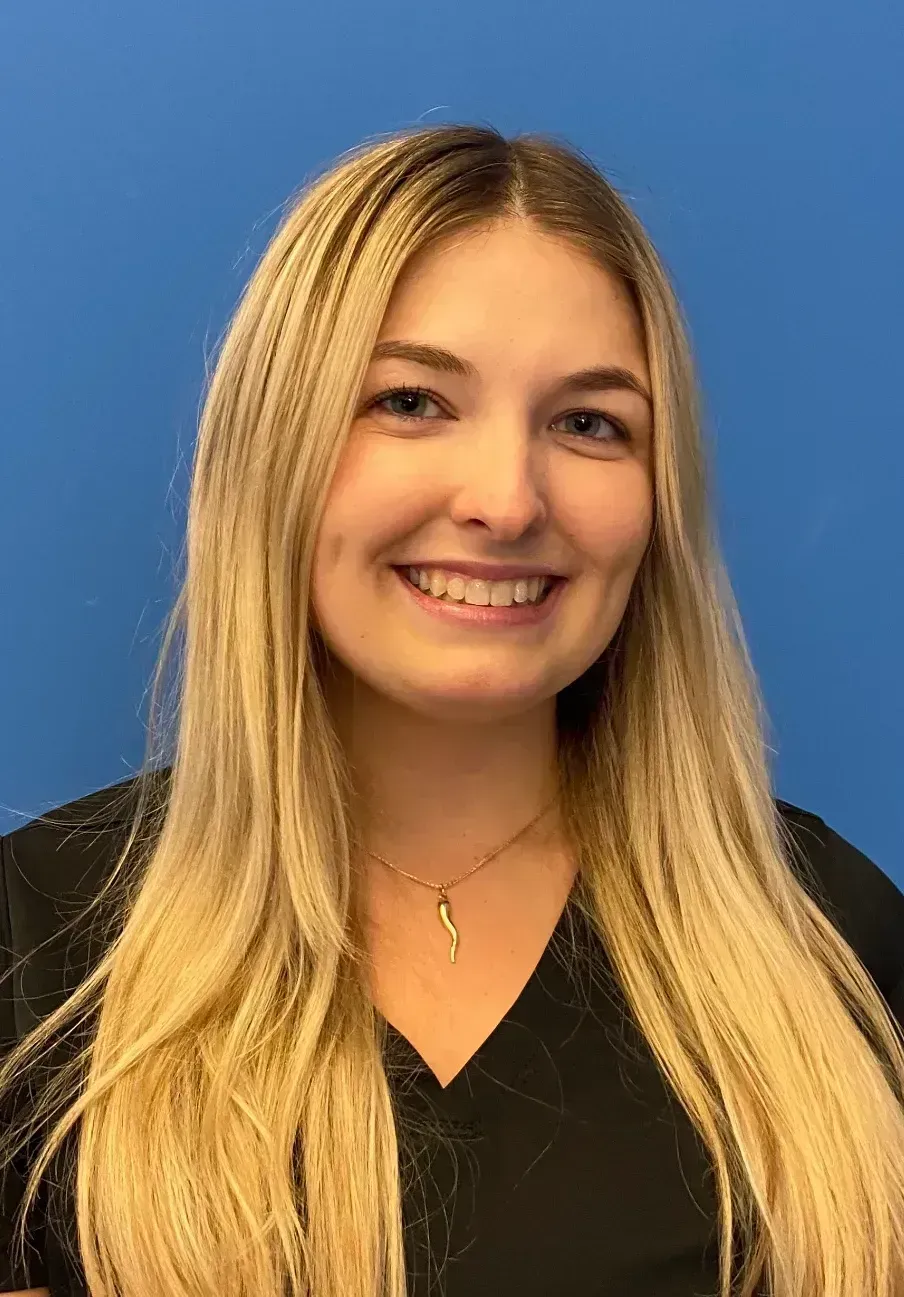 Smiling woman with long blonde hair in a black top against a blue background