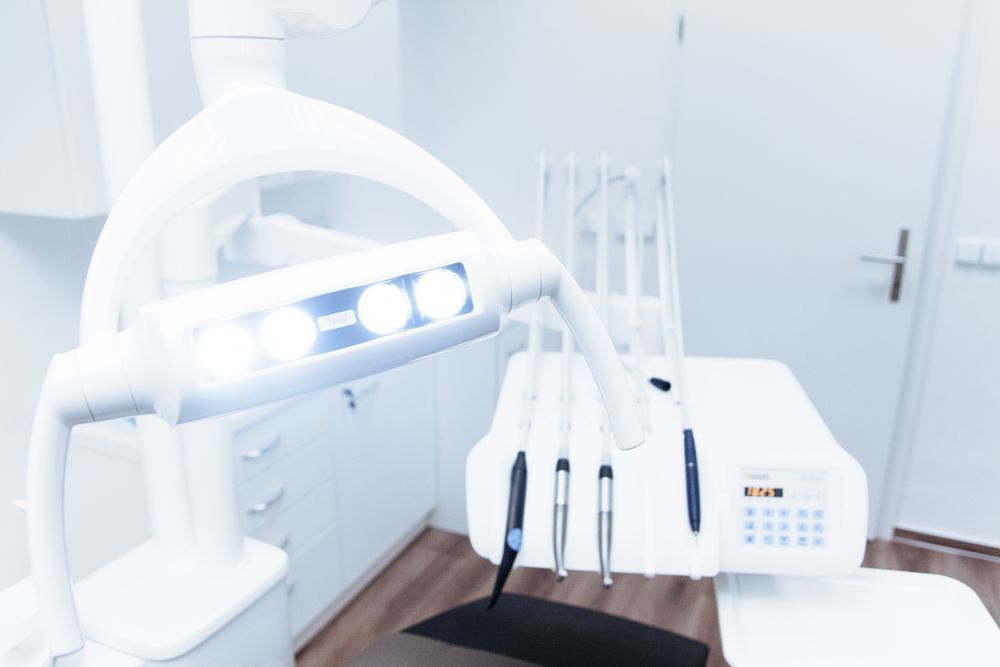 Modern dental clinic with a white dental chair, overhead lights, and treatment equipment