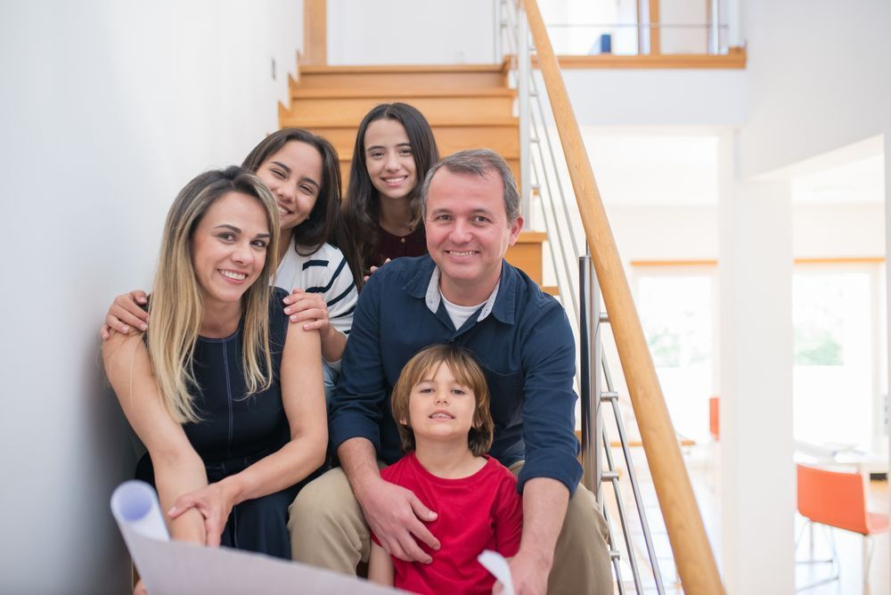 Family posing on a staircase, smiling together in a bright home interior.