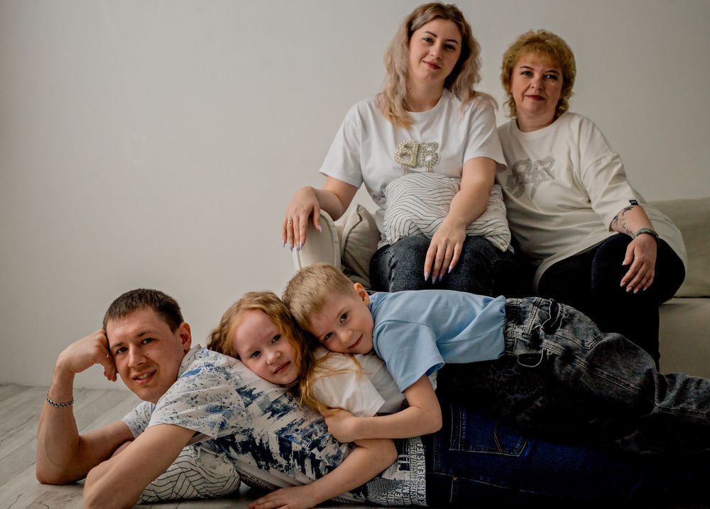 Five people posing together on a couch, relaxed in a casual indoor setting