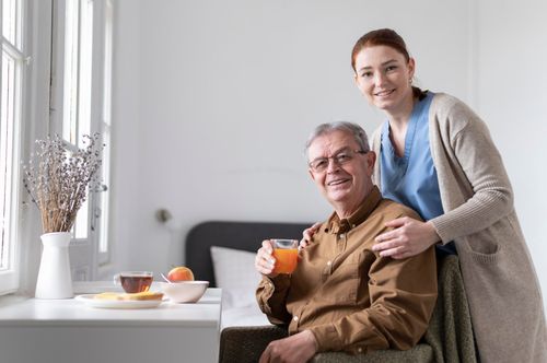 a happy senior having breakfast with his caretkaer