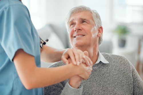 a happy senior holding his caretaker hand