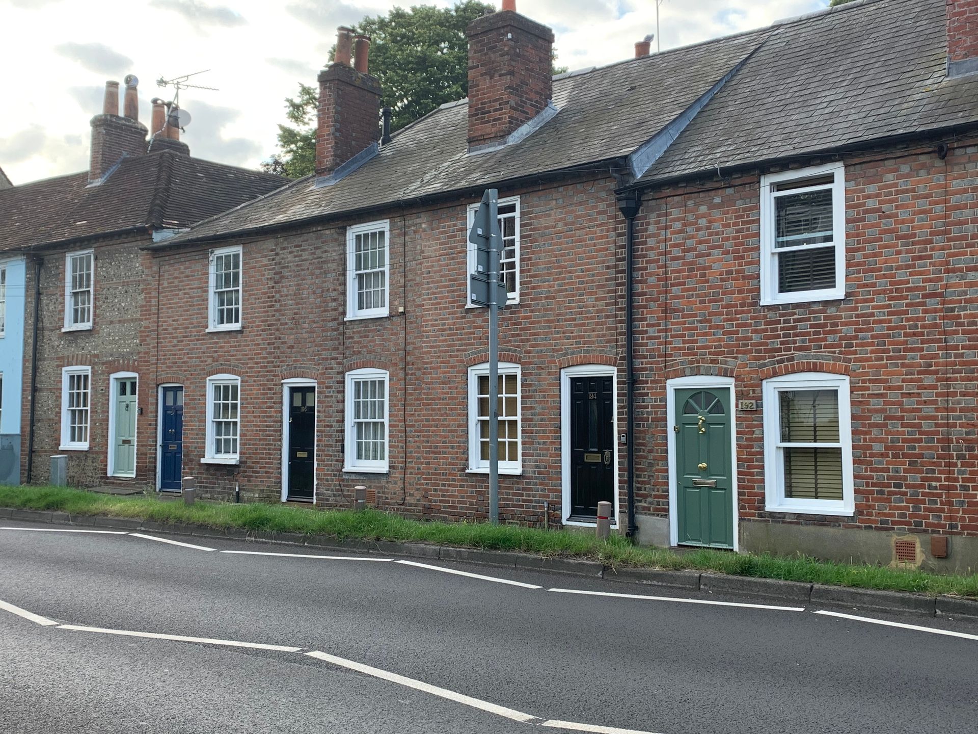 Row of Victorian brick terraced cottages with white-trimmed windows along a curved street