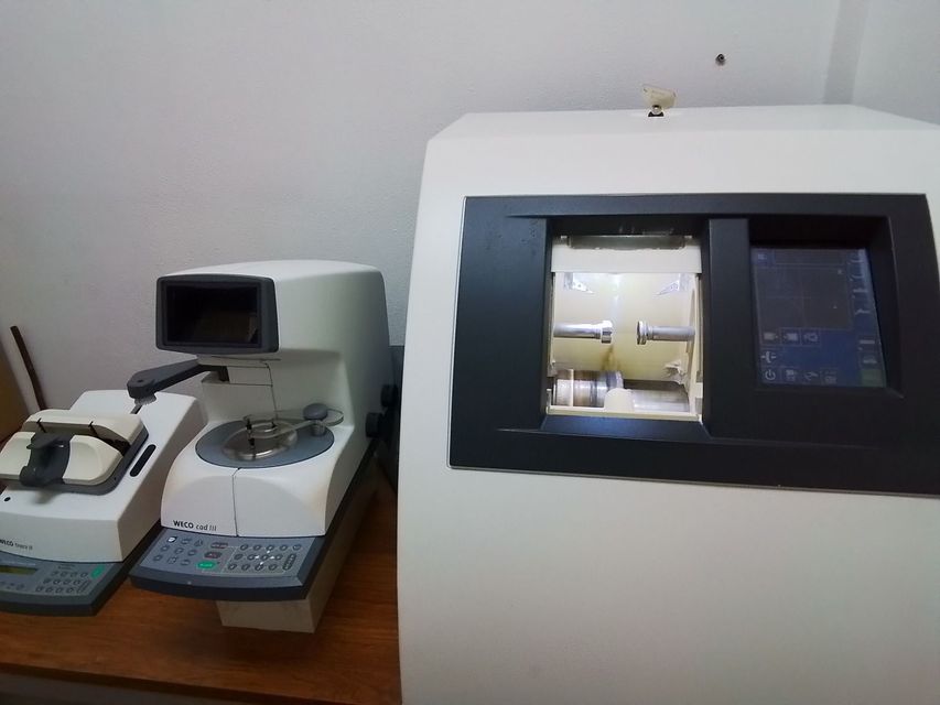 Apparecchiature da laboratorio su un bancone, tra cui un microscopio e un grande analizzatore con schermo.