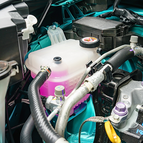 Car engine compartment with coolant reservoir, hoses, and various components.