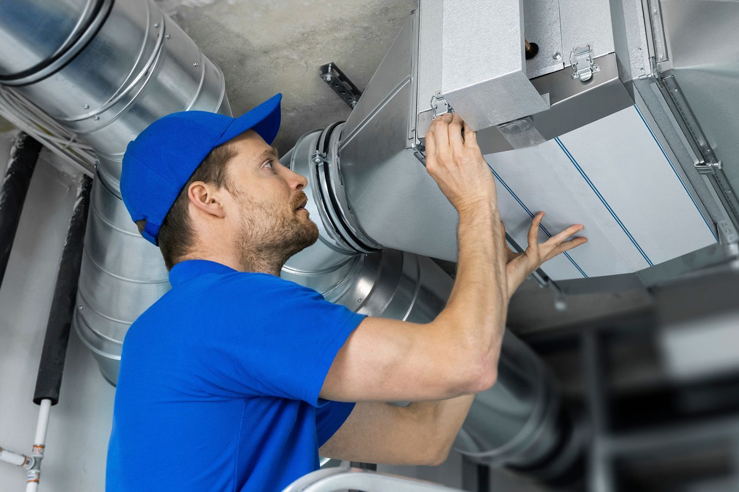 A man is working on a ventilation system in a building.