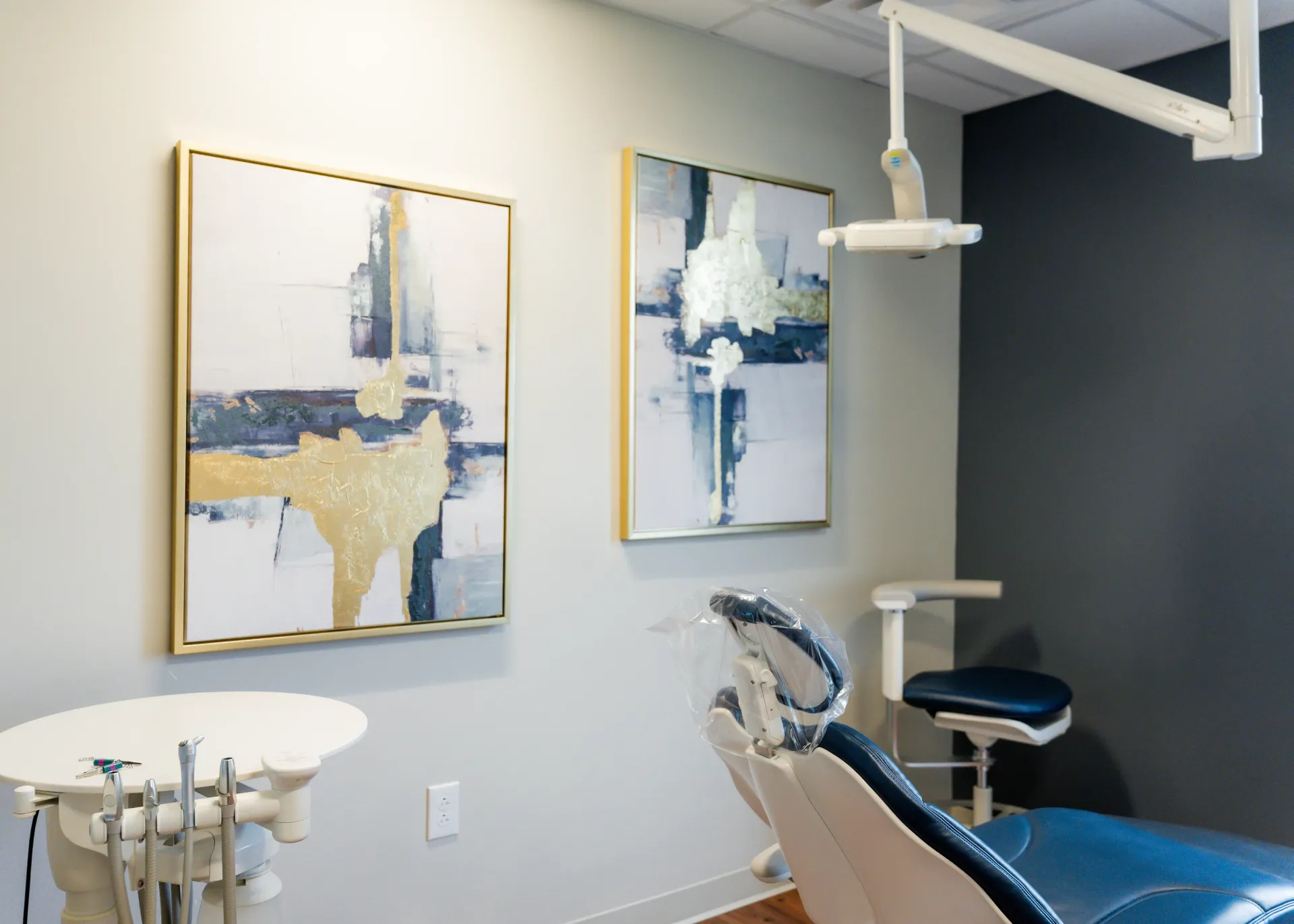 Dental operatory with chair, equipment, art, and overhead light.