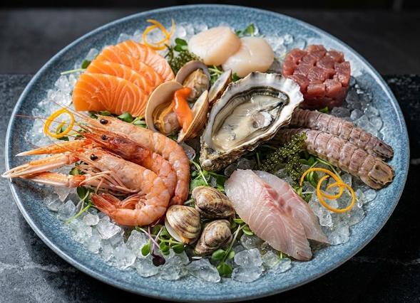 Piatto di frutti di mare su ghiaccio con salmone, gamberi, ostriche, capesante e molluschi su un piatto blu