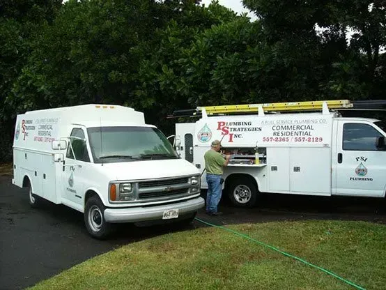 Two white plumbing service trucks of Plumbing Strategies Inc.