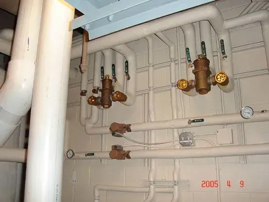 White pipes with valves and insulation, in a mechanical room.